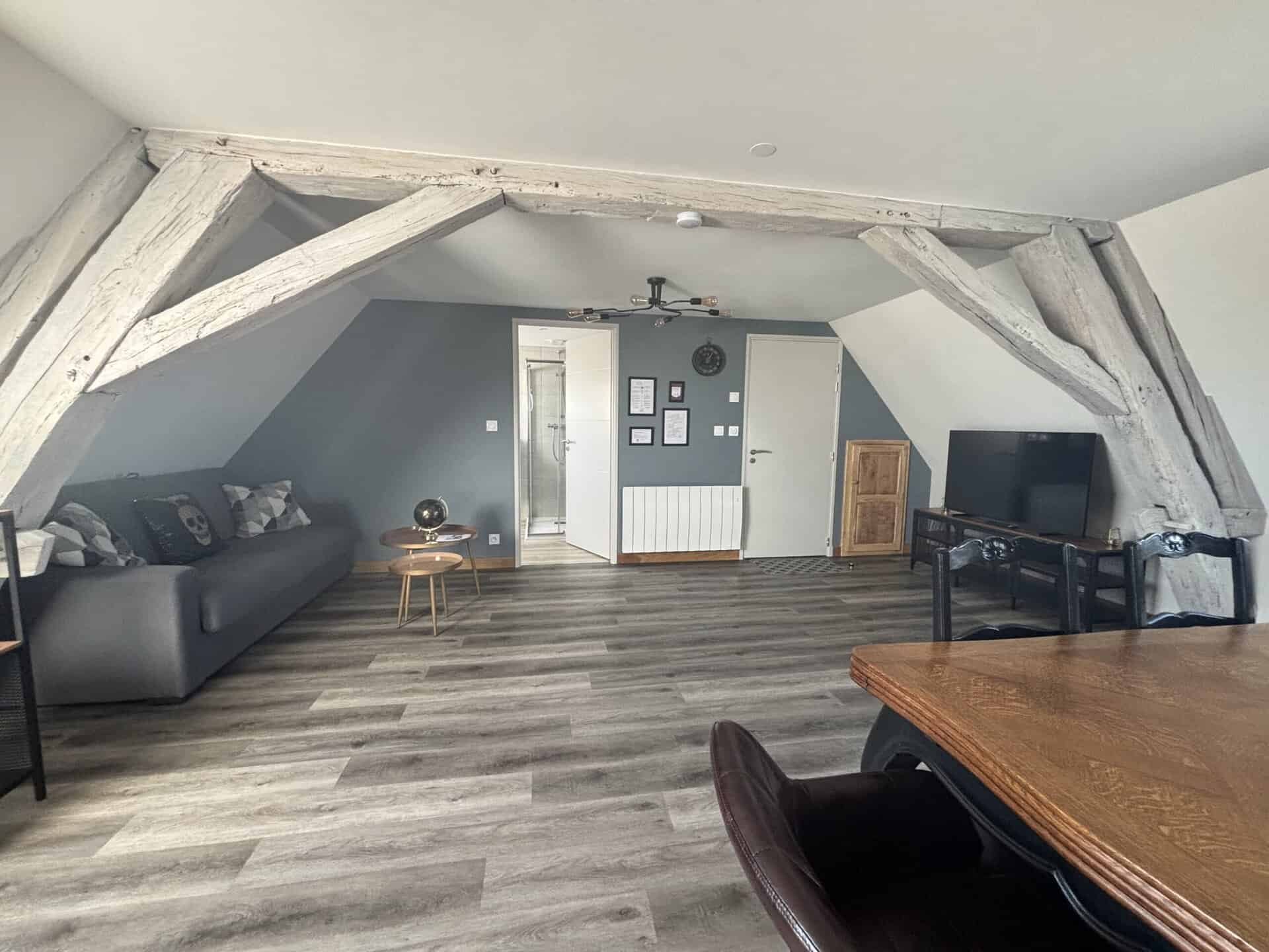 Chambre lumineuse avec lit double, décoration florale et parquet en bois naturel.