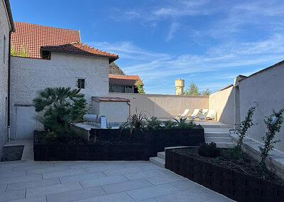 Terrasse ensoleillée avec jardin et vue sur le ciel bleu.