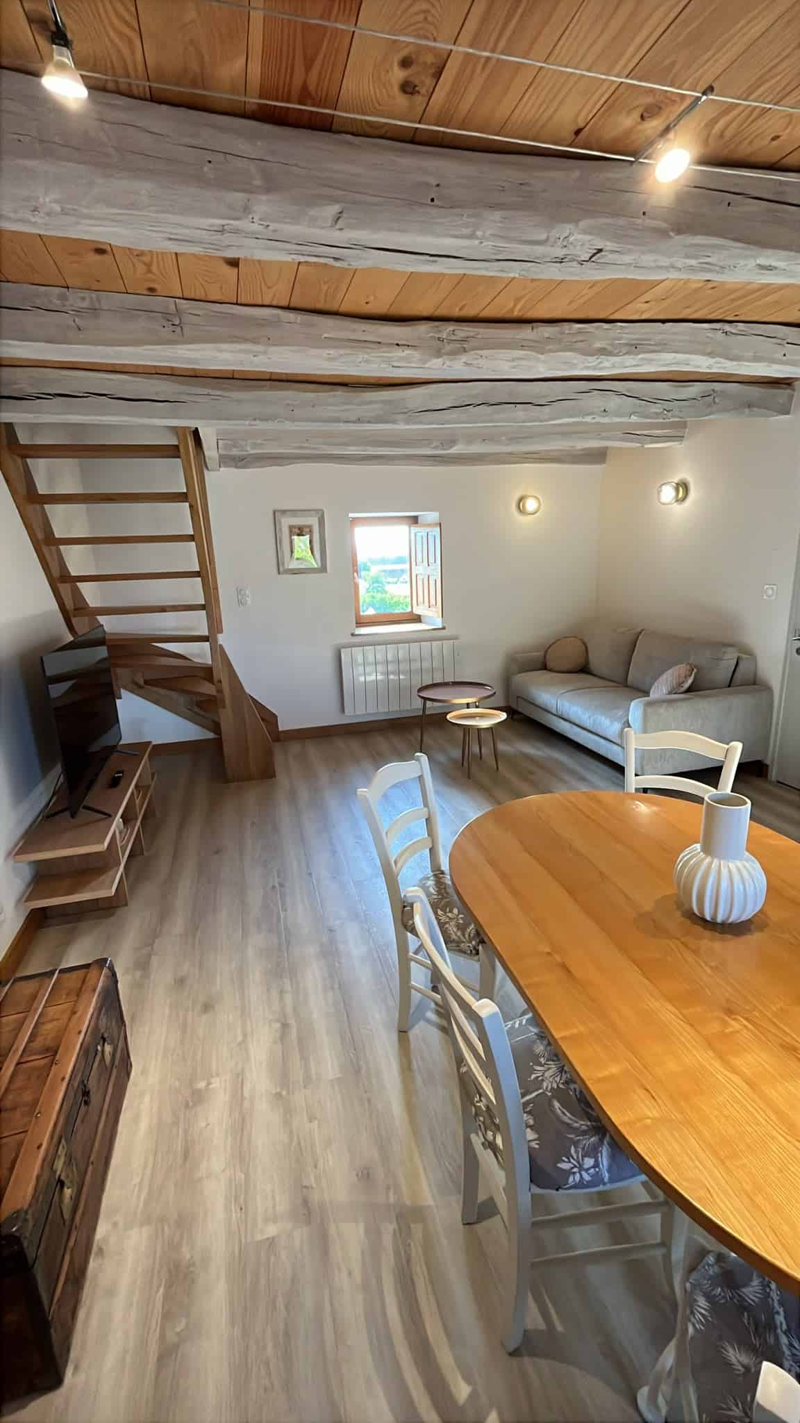 Salon chaleureux à Mesnil Montrivaut Intérieur accueillant avec canapé, table en bois et escalier en bois.